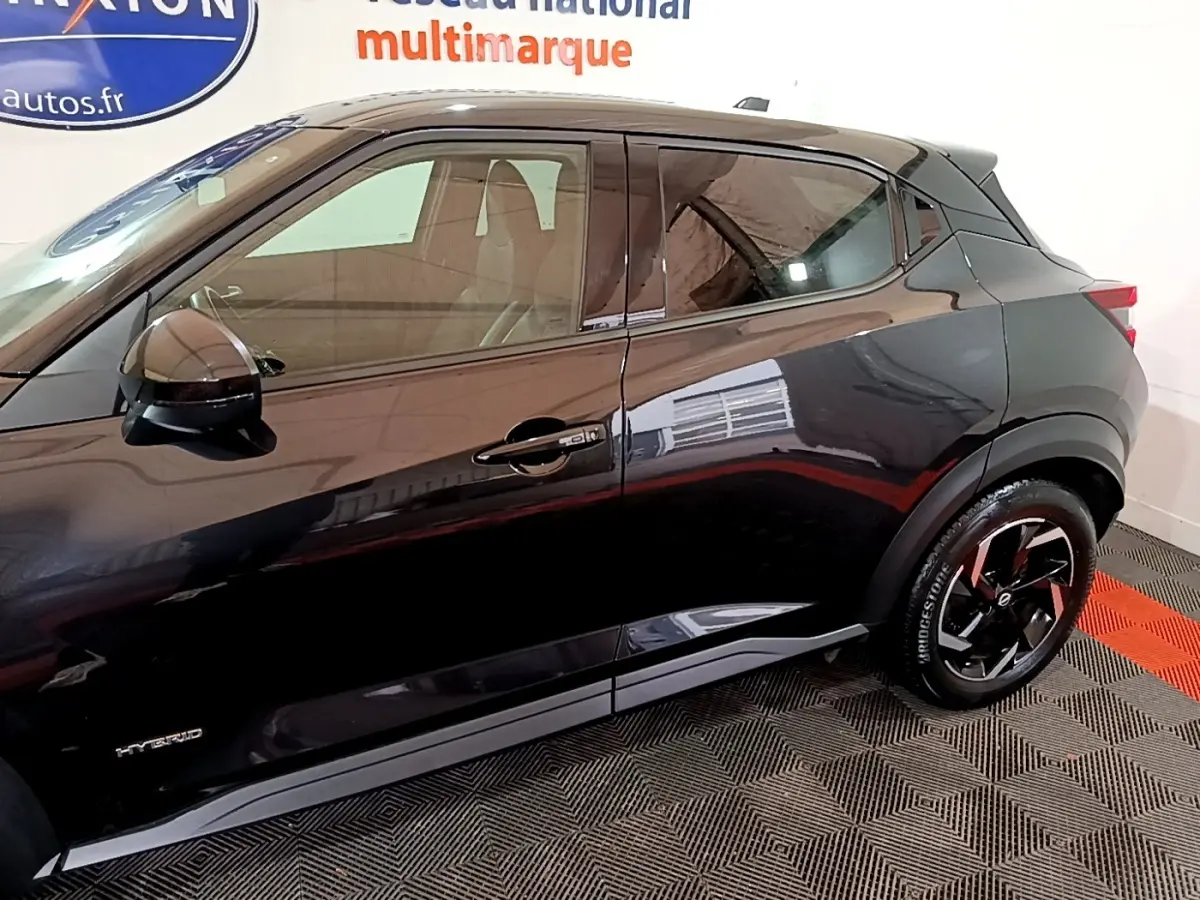 Vue de profil côté droit d'un Nissan Juke Hybrid 143 Business+ noir, mettant en valeur les jantes noires et le badge Hybrid.