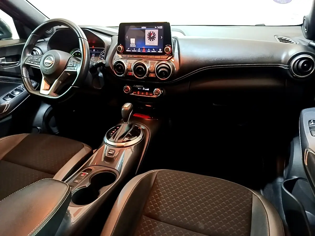 Vue intérieure avant du Nissan Juke Hybrid 143 Business+ 2022, tableau de bord noir avec écran tactile central et volant cuir.