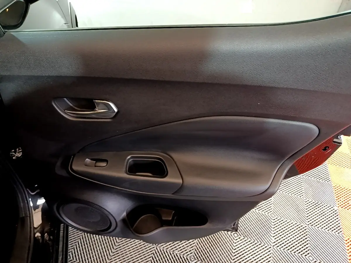 Vue intérieure côté gauche de la porte noire du Nissan Juke Hybrid 2022 avec poignée et haut-parleur intégrés.