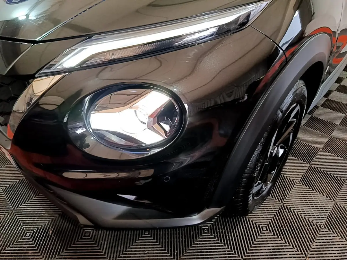 Gros plan sur le phare avant droit du Nissan Juke Hybrid 143 Business+ noir, mettant en valeur son design LED distinctif.