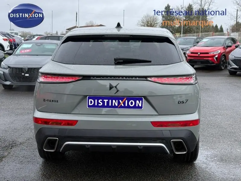Vue arrière d'un DS7 E-TENSE gris 2024 avec feux étirés et logo DS centré sur un parking humide.