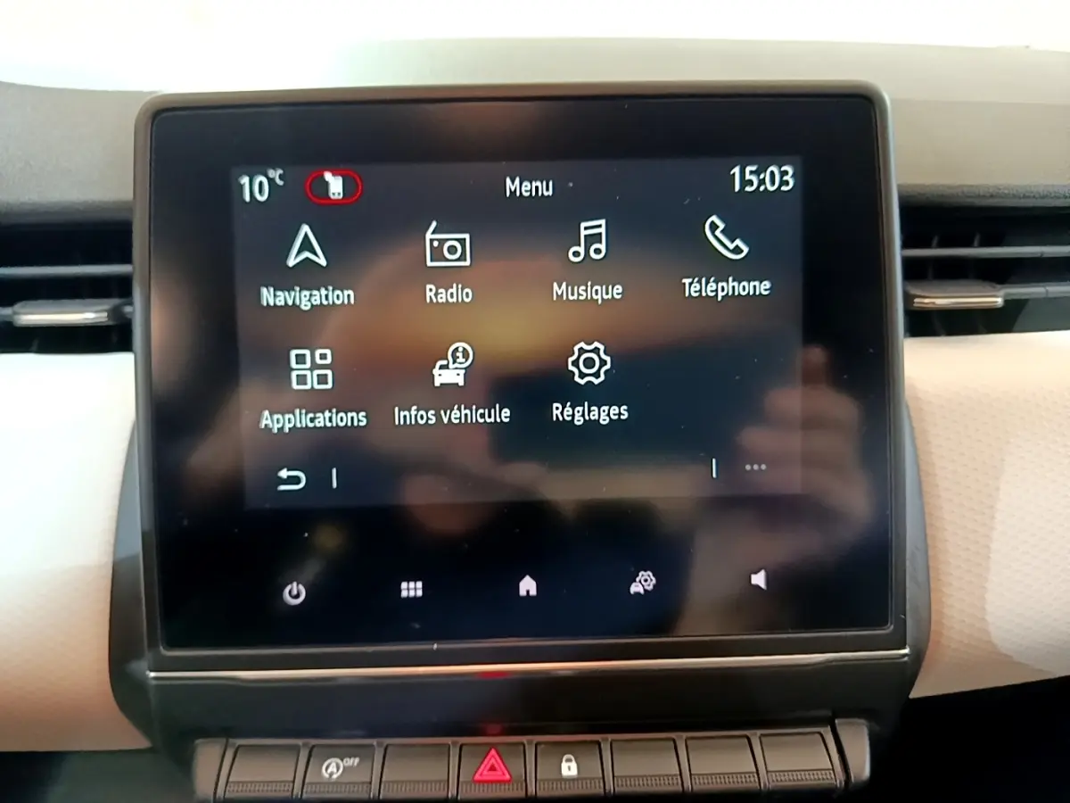 Écran tactile central de la Renault Clio bleu, affichant le menu principal avec navigation et musique.