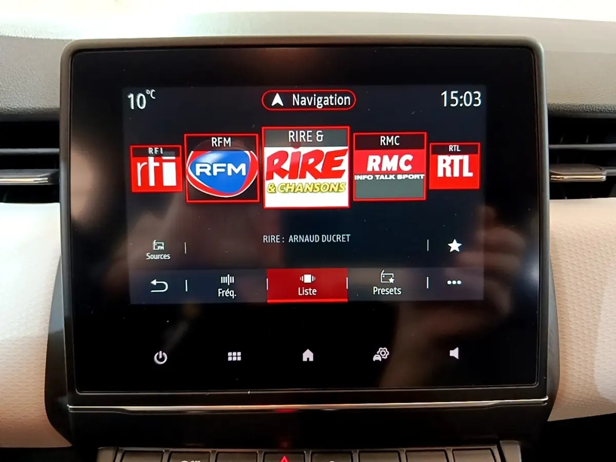 Écran tactile central de la Renault Clio bleu 2022 affichant les stations radio et la navigation.