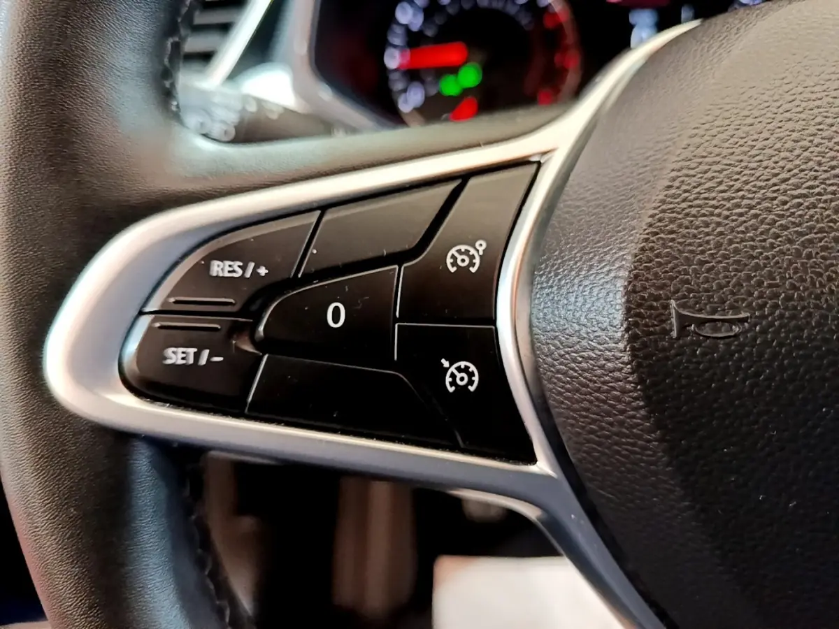 Gros plan sur le volant cuir synthétique de la Renault Clio bleu 2022, avec commandes du régulateur de vitesse.