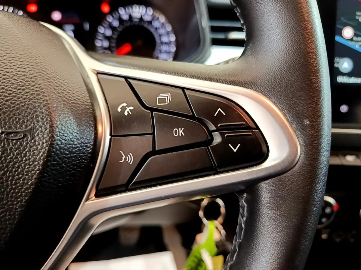 Gros plan sur le côté droit du volant cuir synthétique de la Renault Clio bleu, avec commandes multifonctions visibles.