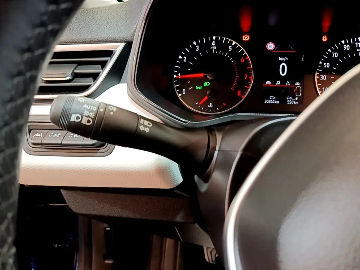 Vue rapprochée du tableau de bord et du commodo d’éclairage d’une Renault Clio bleu, affichage digital au centre.