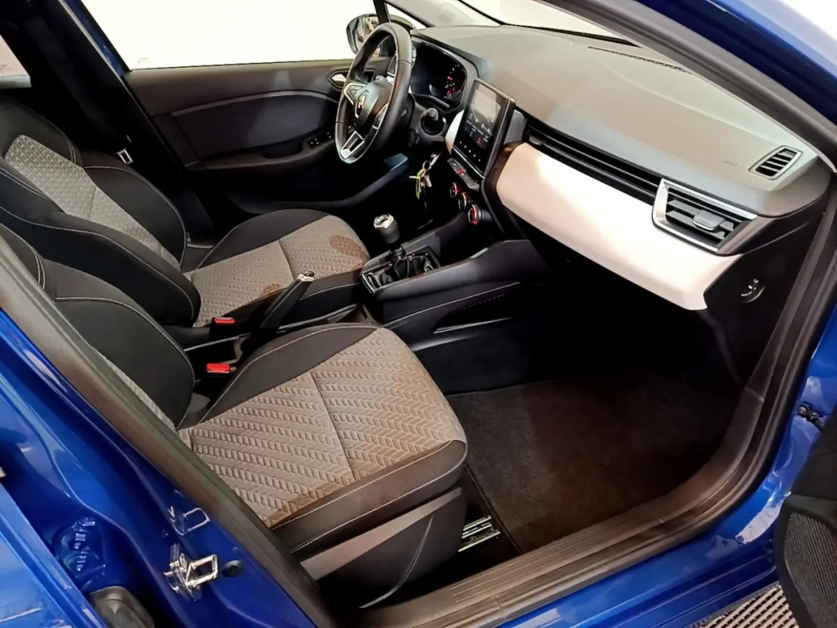 Vue intérieure côté passager de la Renault Clio Evolution bleu 2022, montrant sièges tissu et tableau de bord moderne.