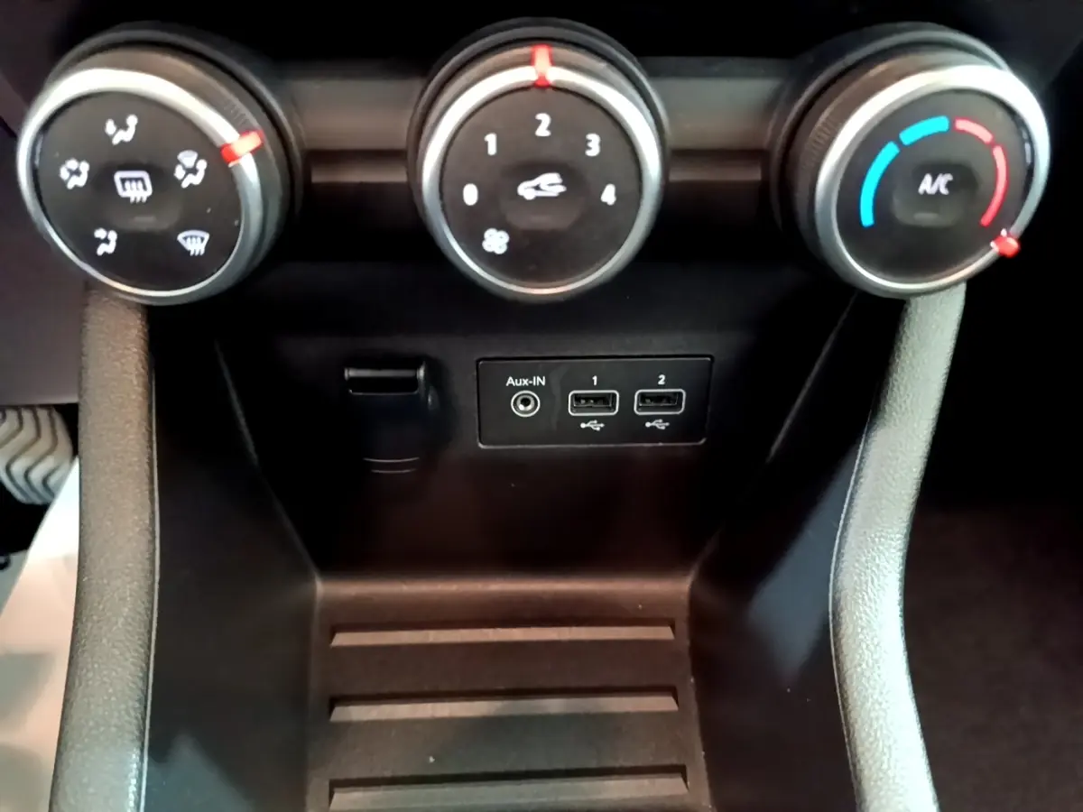 Gros plan sur les commandes de climatisation et les ports USB/Aux d’une Renault Clio Evolution SCe 65, intérieur noir.