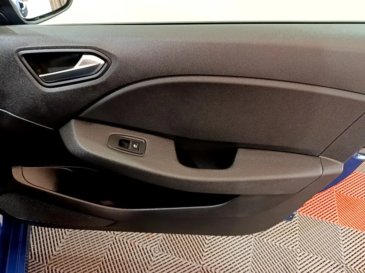 Vue intérieure du panneau de porte côté conducteur d’une Renault Clio bleu 2022, avec commande de vitre électrique.