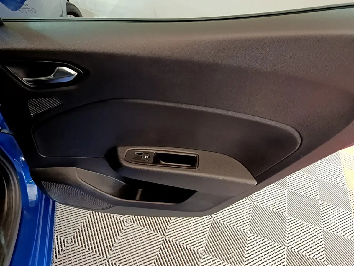 Vue intérieure de la porte avant gauche d’une Renault Clio bleu 2022, avec poignée et commande de vitre noire.
