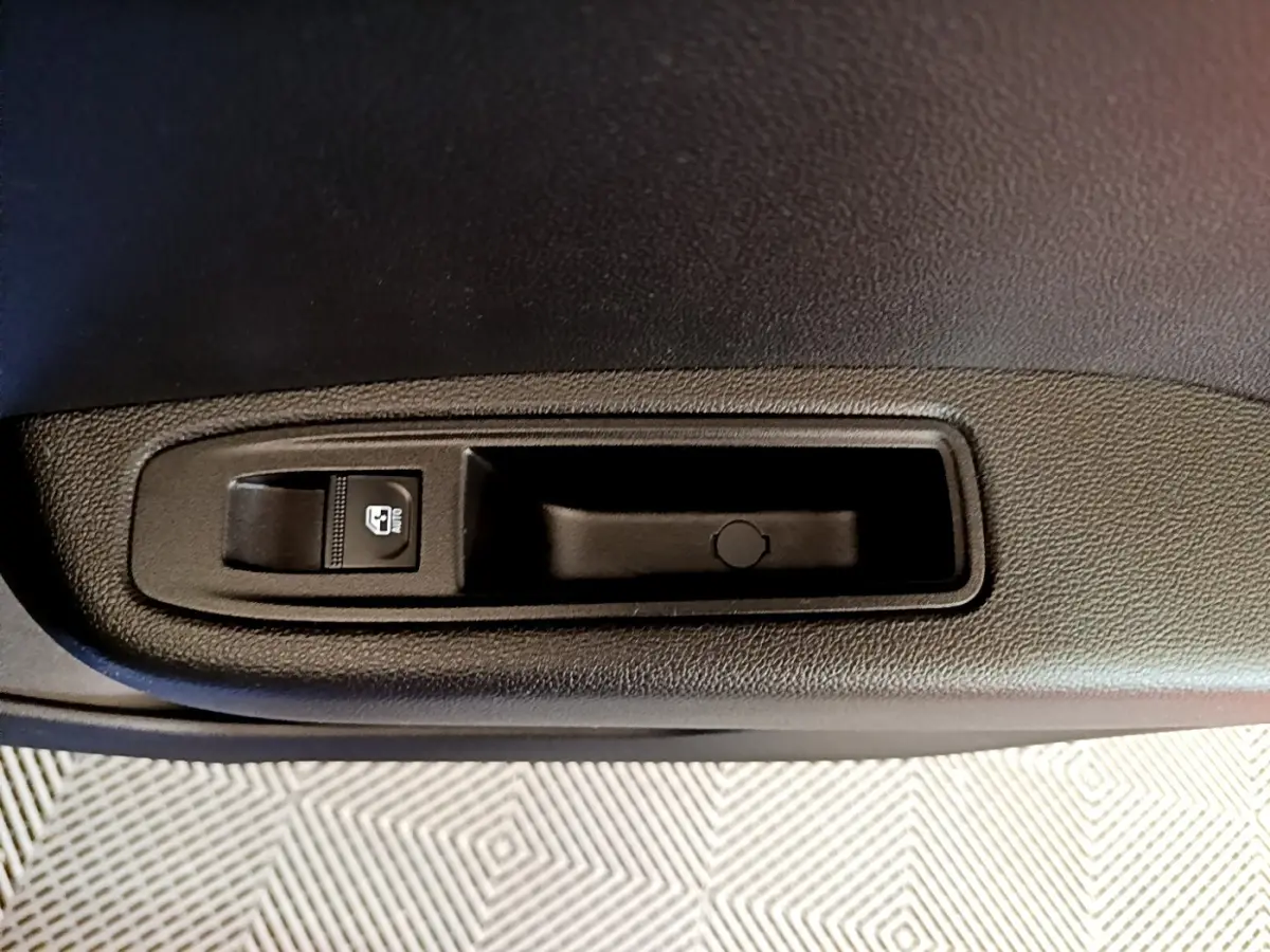 Gros plan sur le bouton de commande de lève-vitre côté conducteur de la Renault Clio bleu 2022.