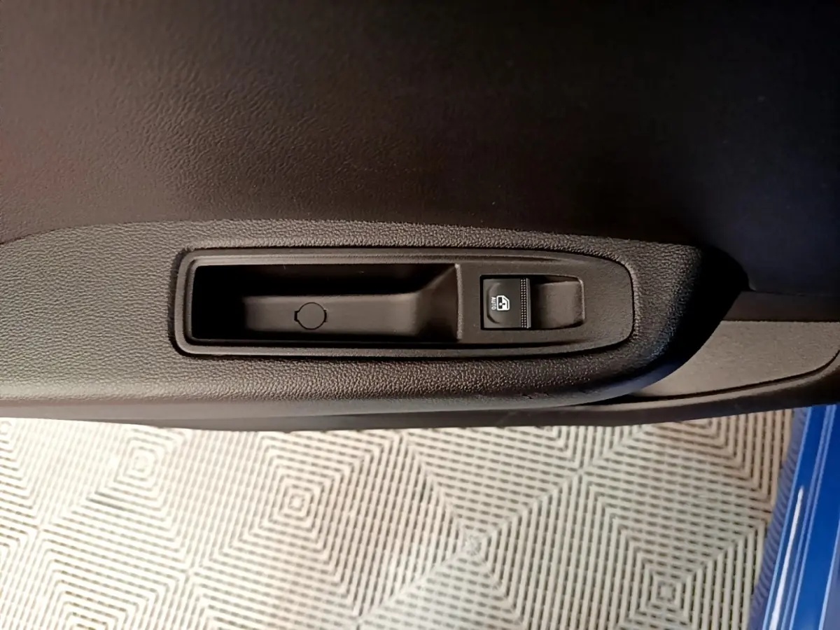 Gros plan sur la commande de lève-vitre côté conducteur de la porte intérieure d'une Renault Clio bleu 2022.