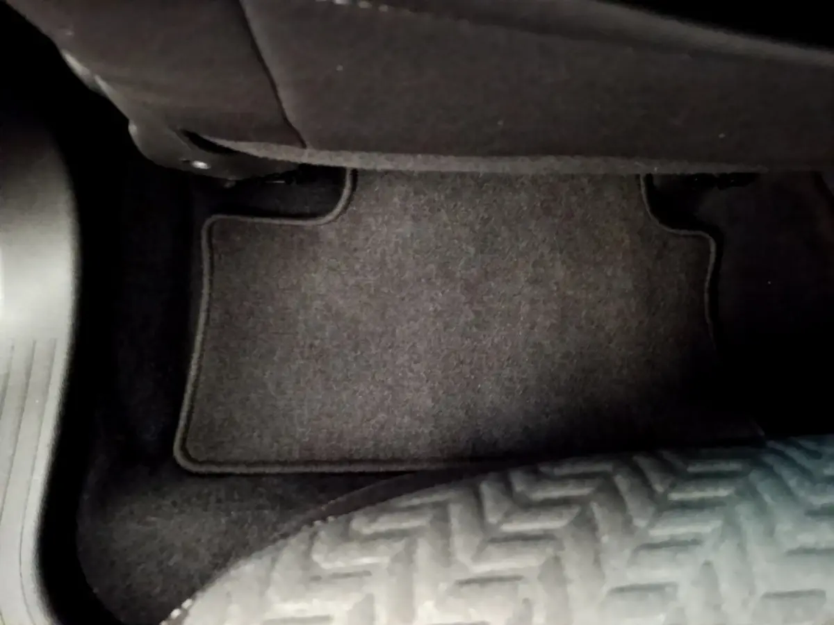 Vue rapprochée du tapis de sol noir côté passager avant de la Renault Clio Evolution bleu 2022.