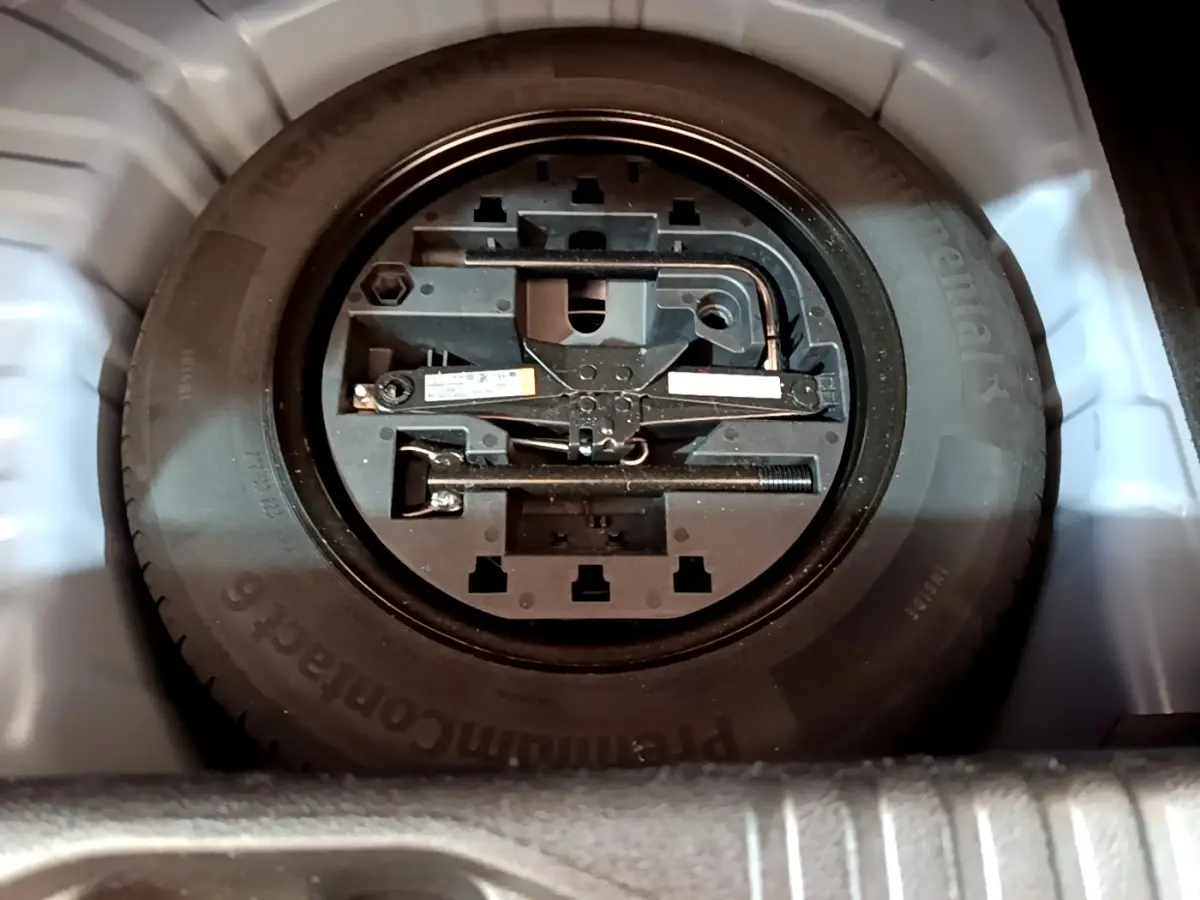 Gros plan sur la roue de secours et les outils de bord dans le coffre d'une Renault Clio bleu 2022.