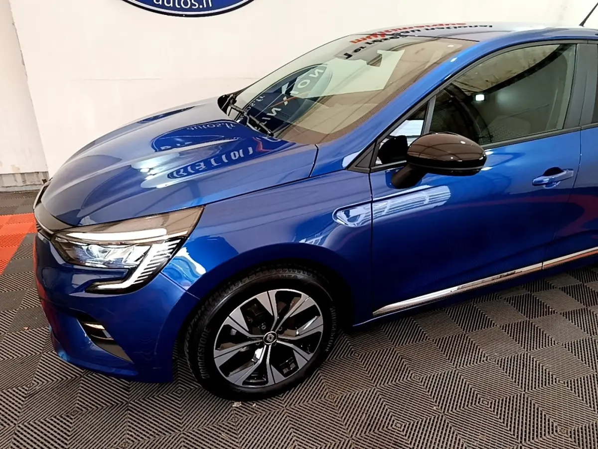 Vue 3/4 avant droit d'une Renault Clio bleu brillant avec jantes alliage et rétroviseurs noirs ton caisse.