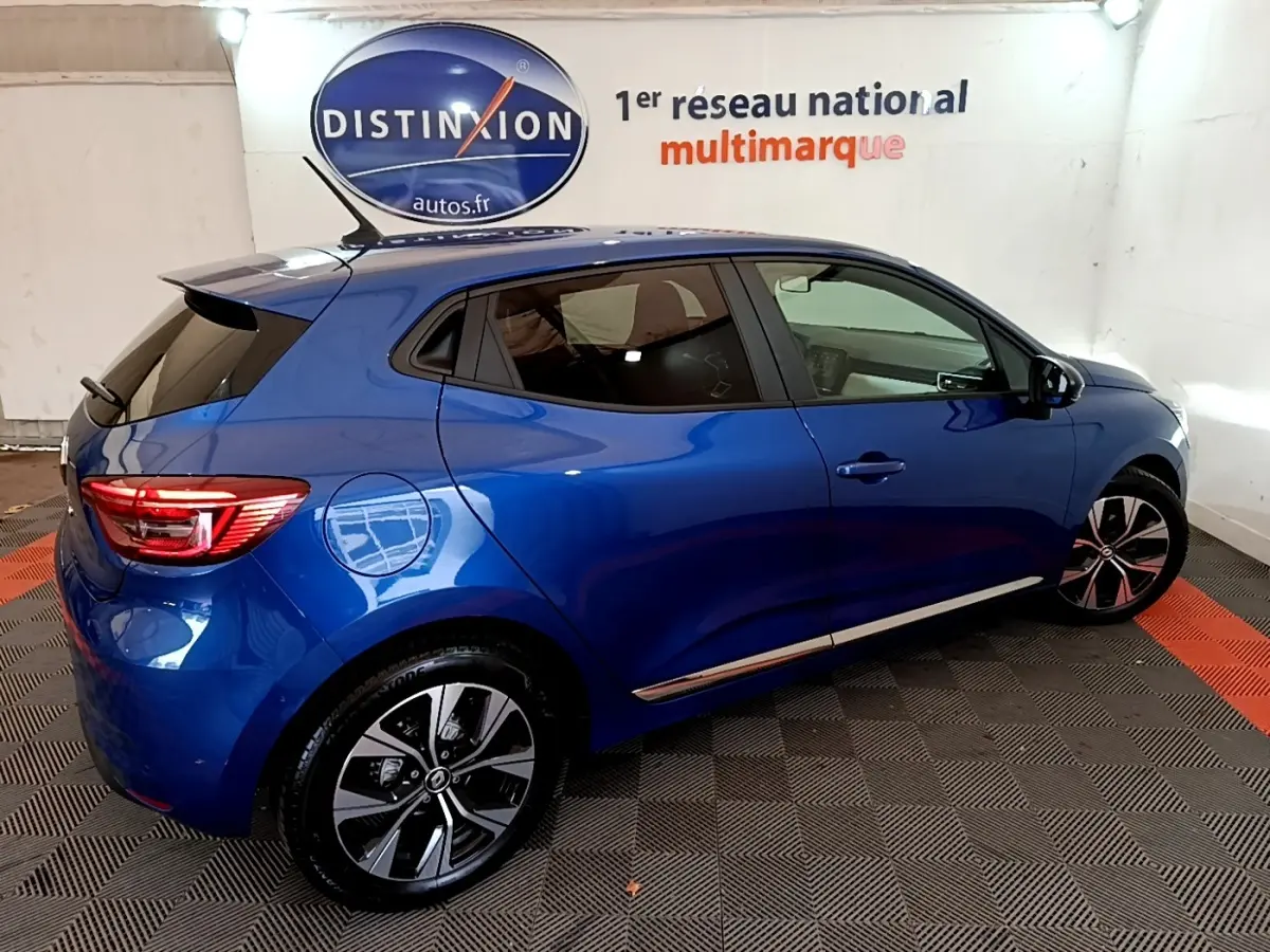 Vue côté droit arrière d'une Renault Clio Evolution bleu 2022 avec jantes alliage et toit spoiler noir.
