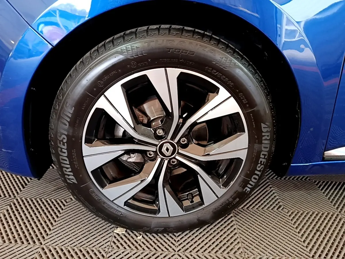 Gros plan sur la roue avant droite d’une Renault Clio bleu, jante alliage bicolore avec logo Renault central.