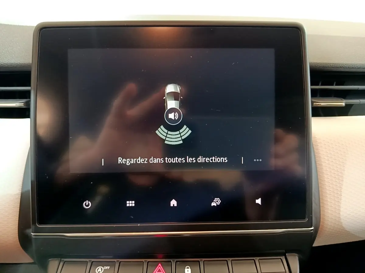 Écran tactile central de la Renault Clio Evolution bleu 2022 affichant l'aide au stationnement avec message de vigilance.