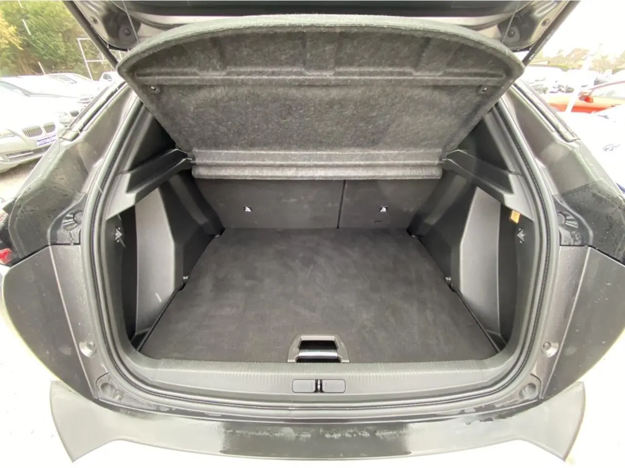 Coffre ouvert vu de l'arrière d'un Peugeot 2008 gris foncé, montrant un espace de chargement propre et spacieux.