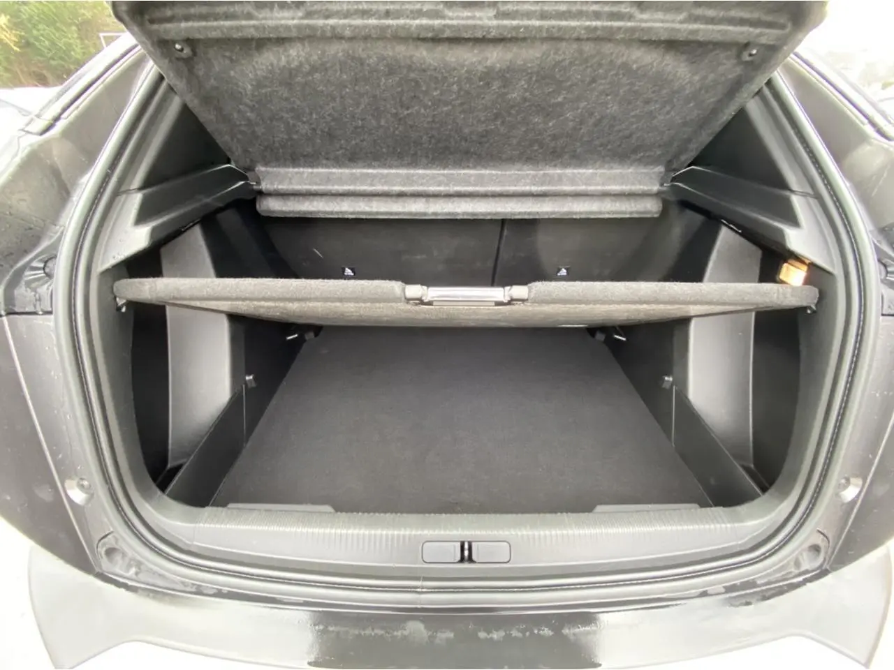 Coffre ouvert vu de l’arrière d’un Peugeot 2008 gris foncé, montrant l’espace de rangement et la tablette cache-bagages.