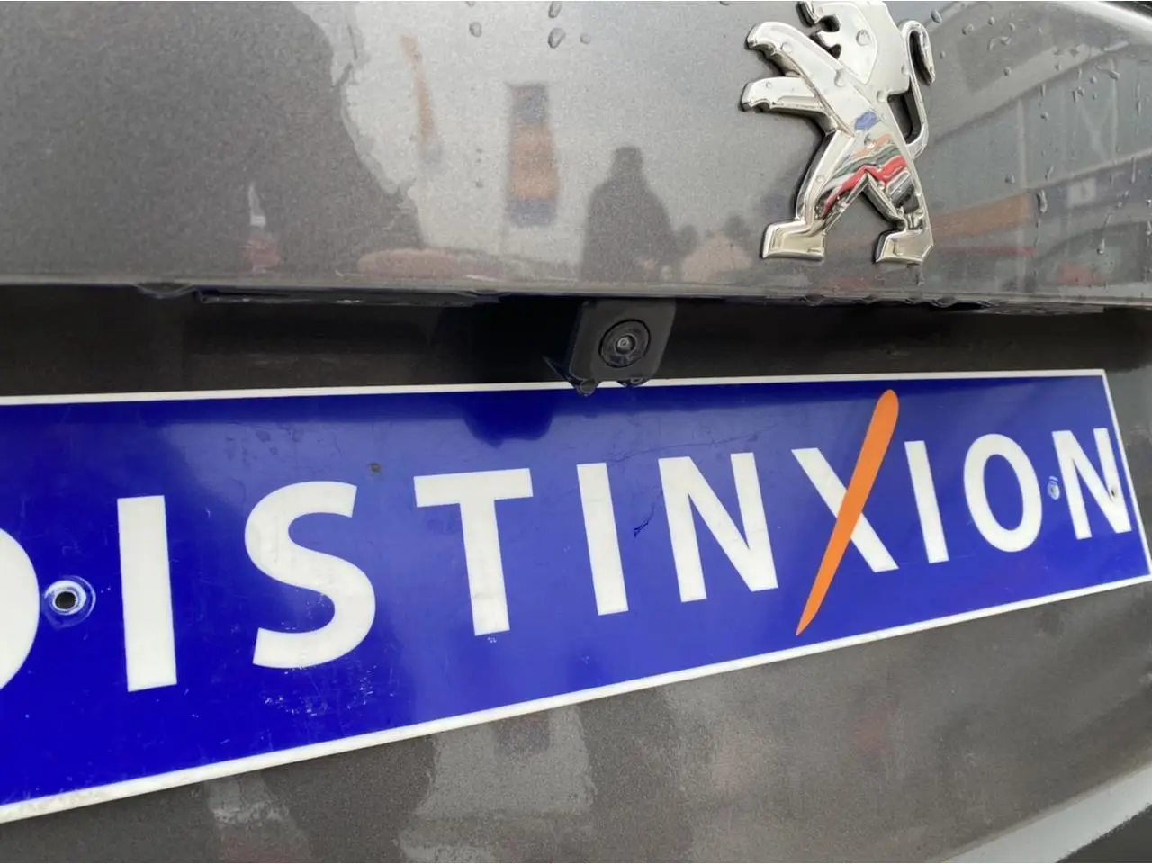 Gros plan arrière sur la caméra de recul et le logo Peugeot d'une 2008 gris foncé avec plaque Distinxion.
