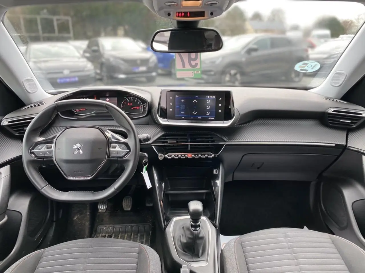 Vue intérieure avant du Peugeot 2008 2021, tableau de bord noir avec écran tactile et volant compact multifonctions.