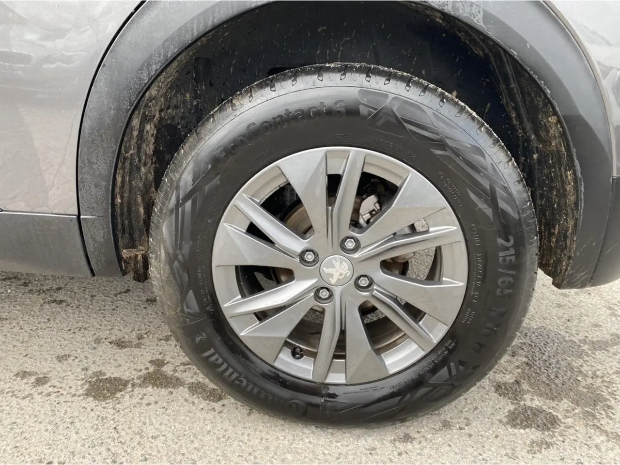 Gros plan sur la roue avant droite du Peugeot 2008 gris foncé, jante alliage avec logo lion au centre.
