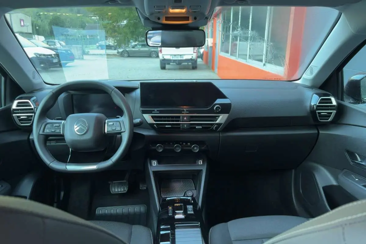 Vue intérieure avant centrée sur le tableau de bord et le volant cuir multifonctions de la Citroën C4 hybride 2025.