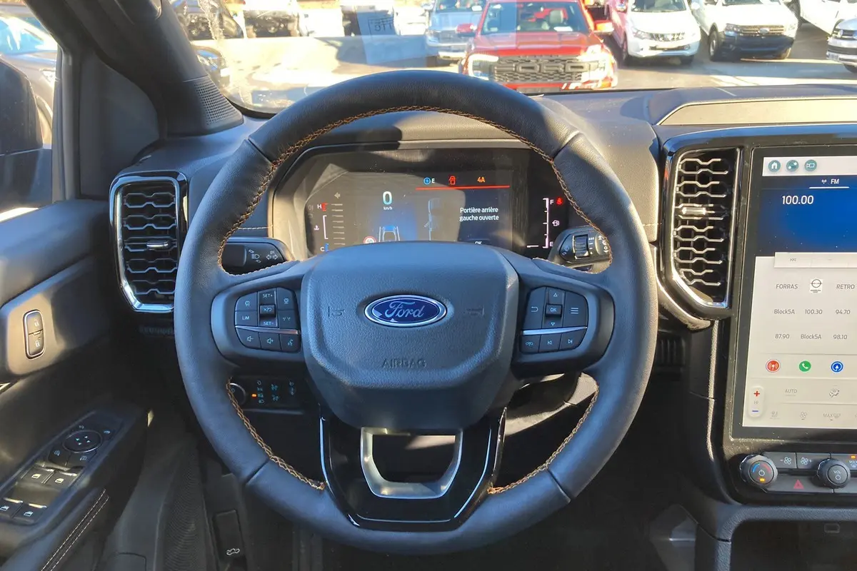 Vue intérieure centrée sur le volant cuir multifonctions du Ford Ranger bleu lightning avec tableau de bord digital et écran tactile.