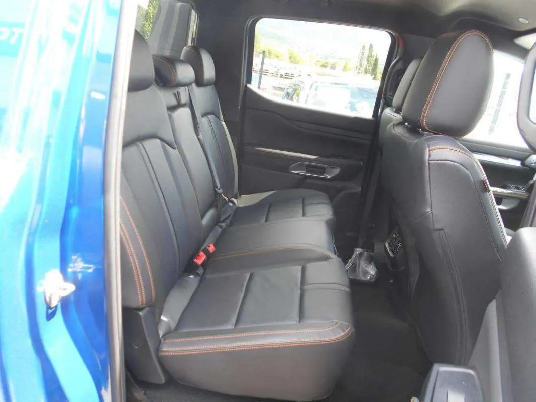 Vue intérieure côté gauche des sièges arrière en cuir noir avec surpiqûres orange du Ford Ranger Bleu Lightning 2025 Wildtrak Plus.