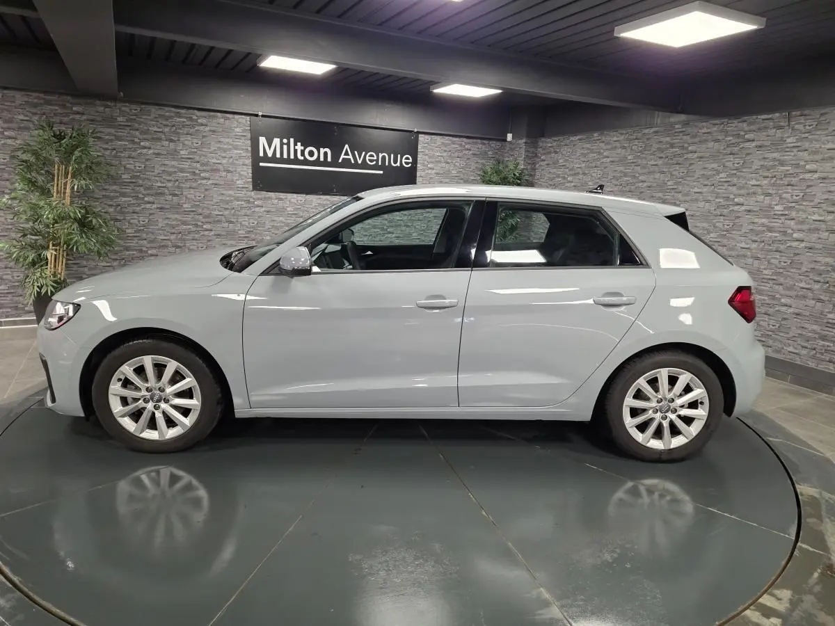 Profil côté gauche d'une Audi A1 Sportback gris Manhattan avec jantes aluminium 16 pouces en showroom.