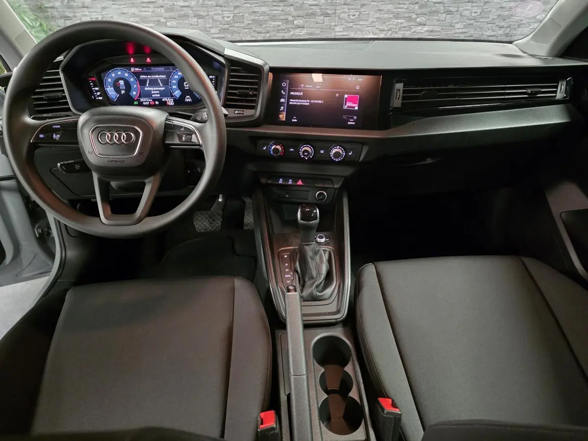 Intérieur de l'Audi A1 Sportback 2020 vu de face, tableau de bord noir avec volant multifonction et écran tactile central.
