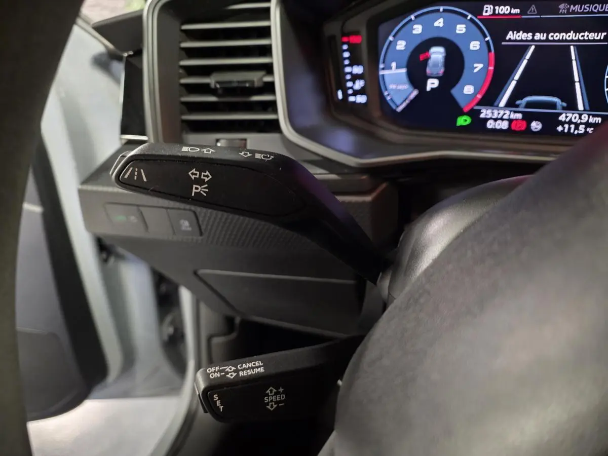 Gros plan sur les commandes au volant et le tableau de bord numérique d'une Audi A1 Sportback gris Manhattan.