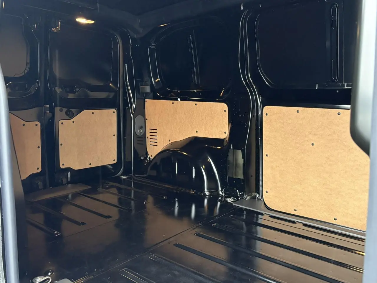Intérieur de la zone de chargement du Citroën Jumpy noir Perla, vue latérale droite avec panneaux de protection bois.