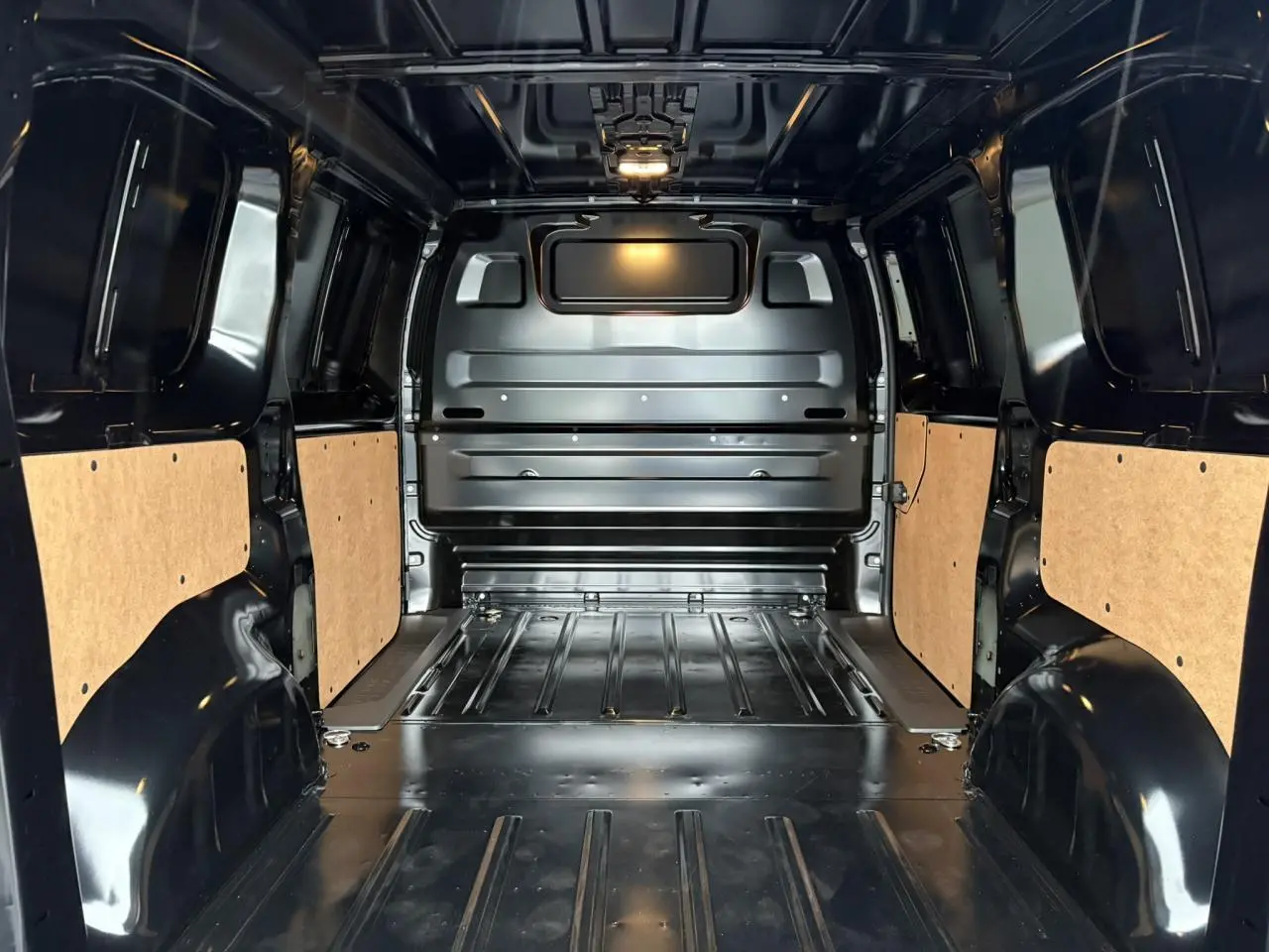Intérieur du coffre noir Perla du Citroën Jumpy M 2025, vue de l'arrière avec parois latérales protégées en bois clair.