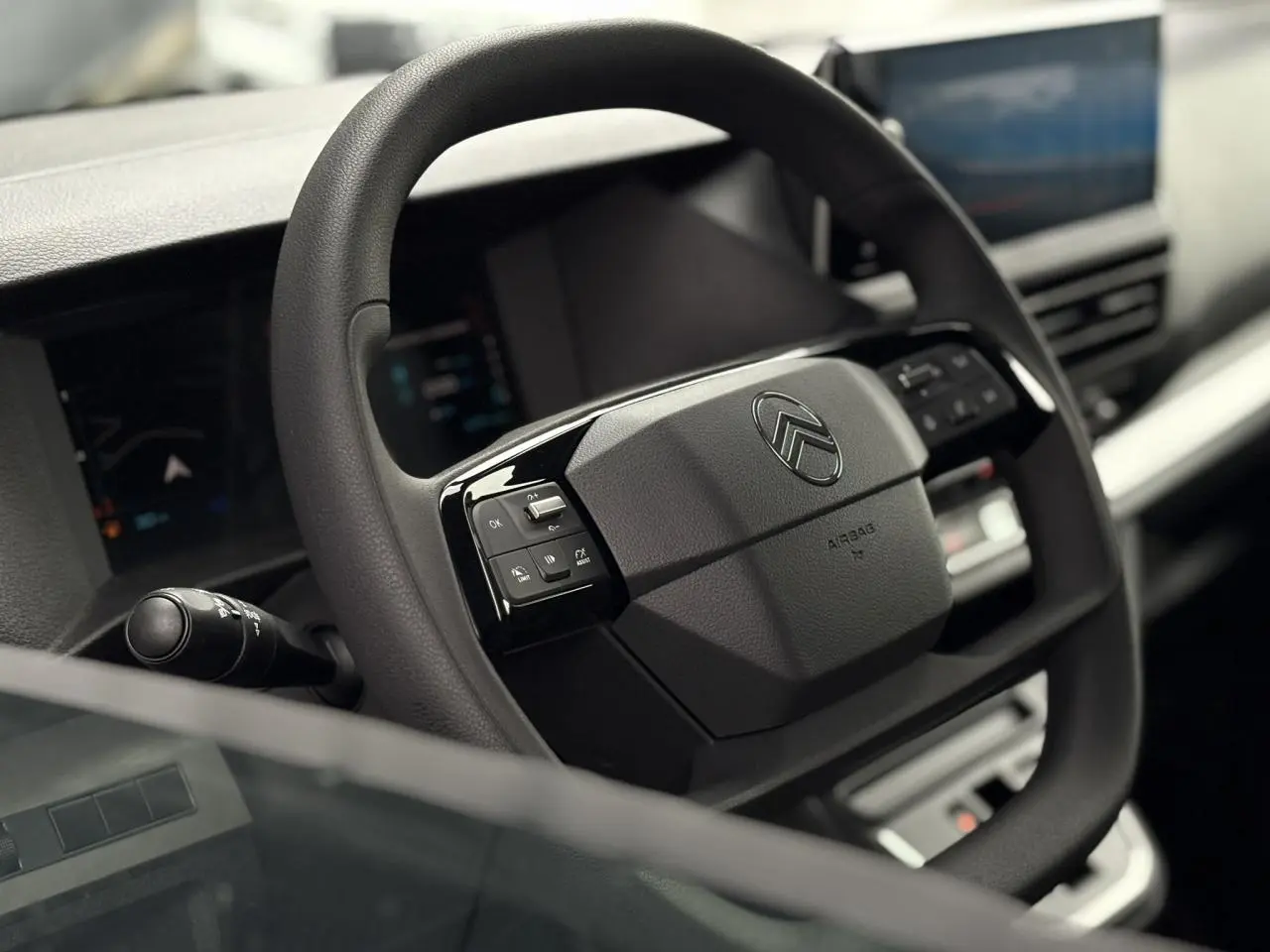 Volant noir de Citroën Jumpy 2025 avec commandes intégrées, tableau de bord numérique et écran tactile en arrière-plan.