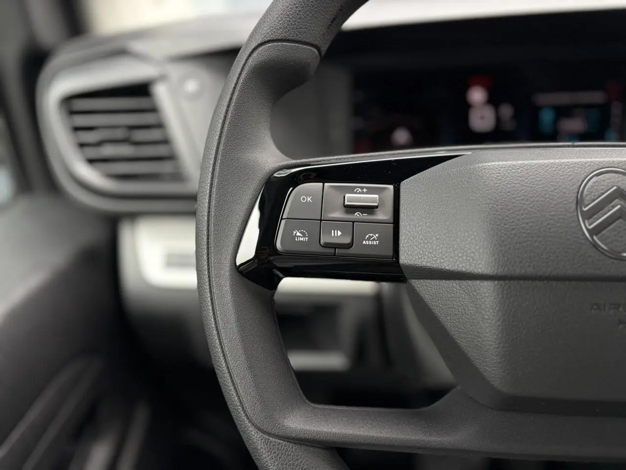 Gros plan sur les commandes au volant noir du Citroën Jumpy 2025, avec logo et tableau de bord flou en arrière-plan.