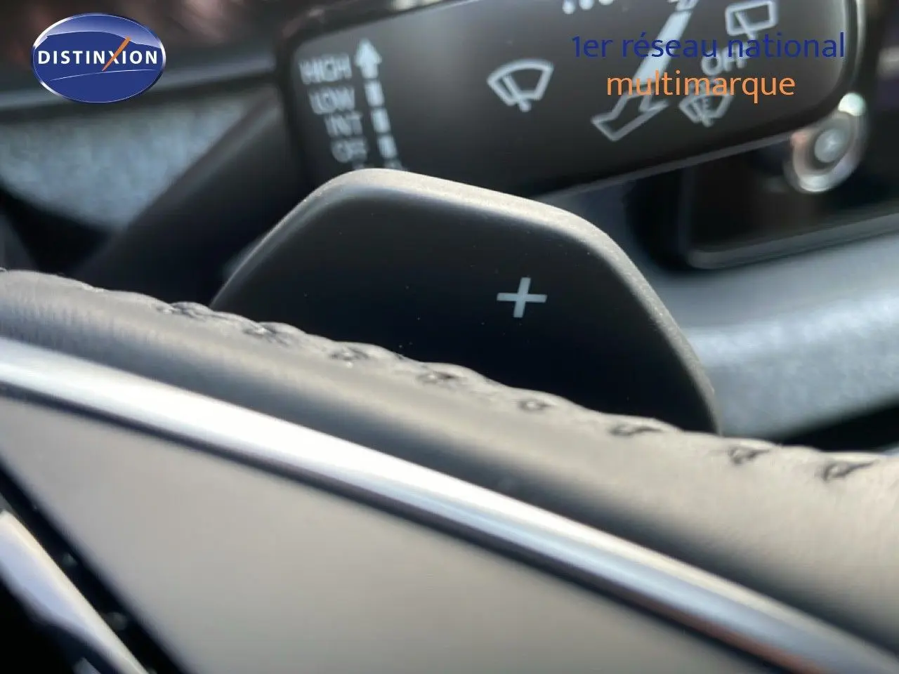 Gros plan sur la palette de changement de vitesse "+" en plastique noir derrière le volant cuir du Skoda Kamiq gris argent 2025.