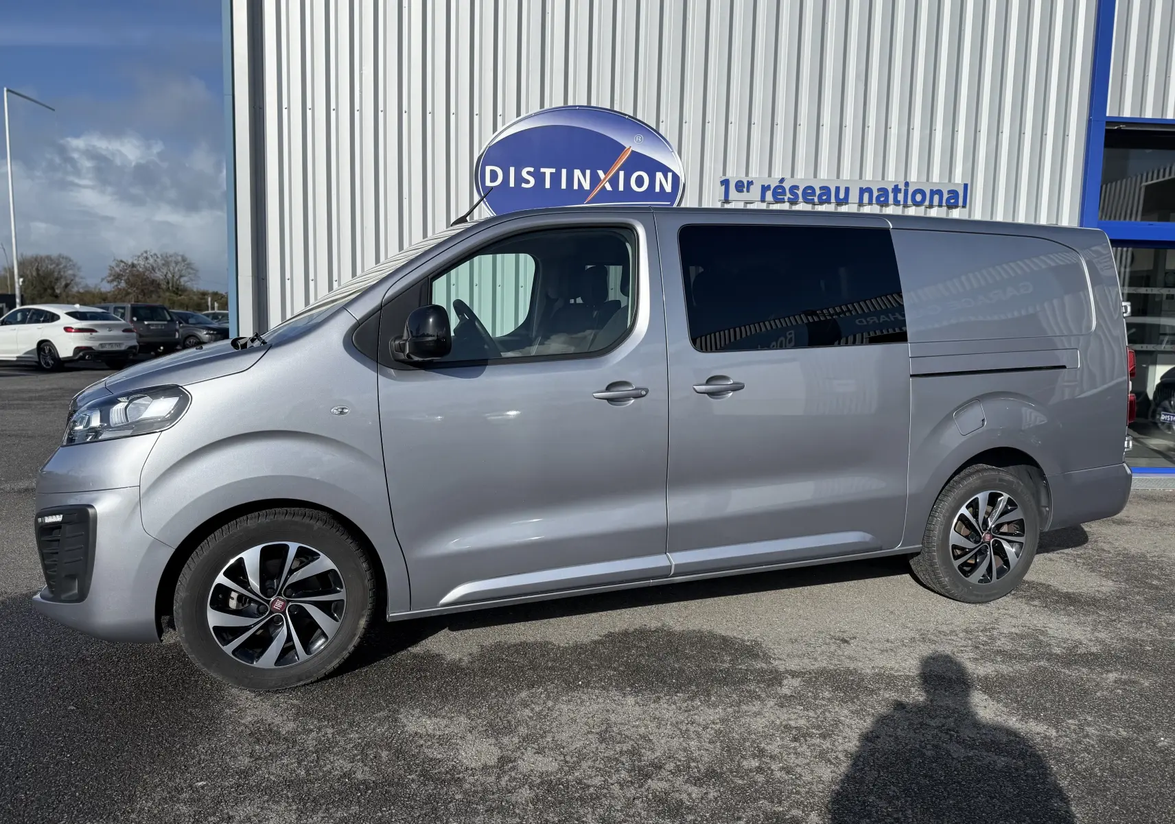 Vue de profil côté gauche d'un FIAT Scudo cabine approfondie gris 2022 avec vitres arrière teintées et jantes bi-ton.