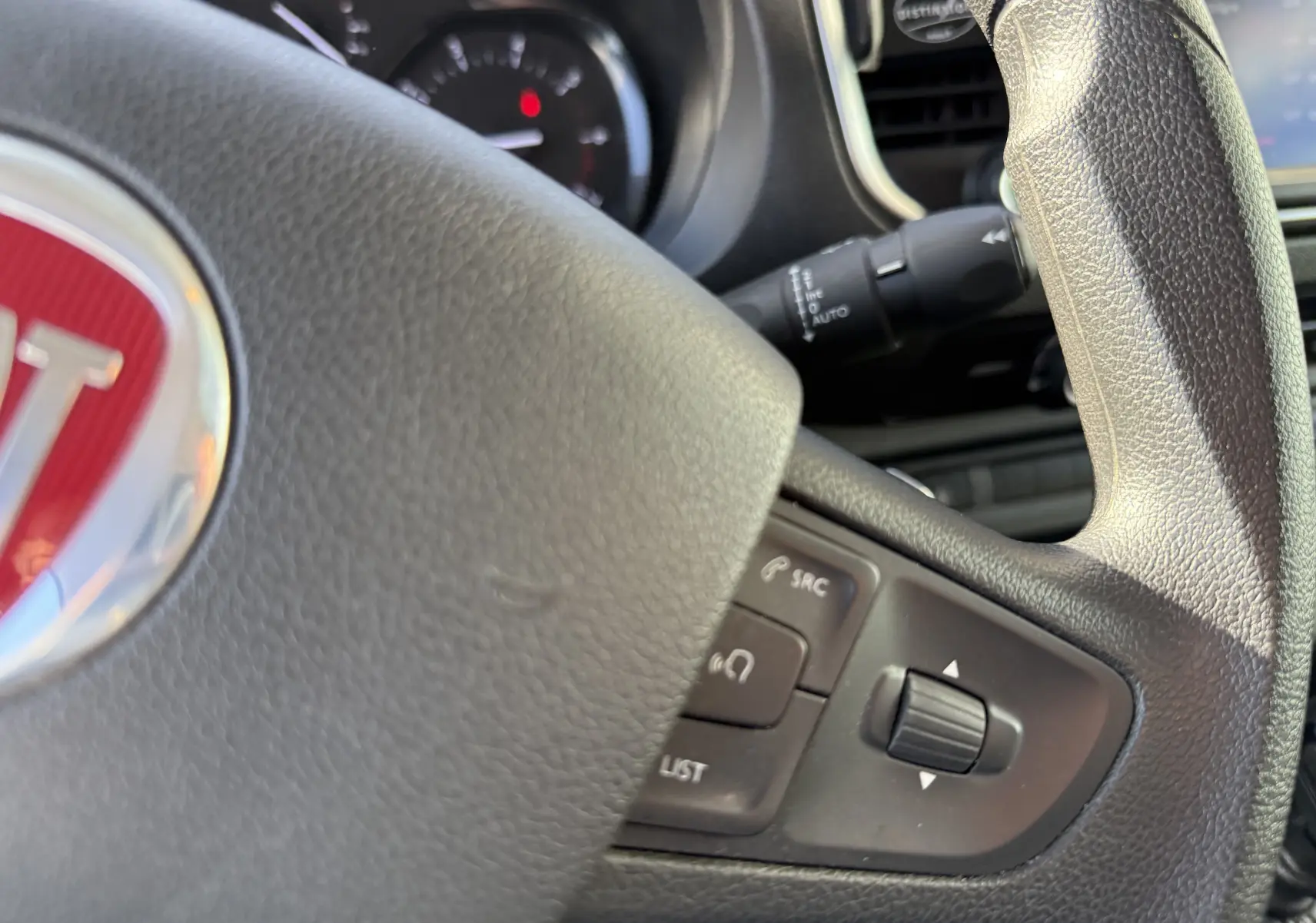 Gros plan sur le volant noir du FIAT Scudo 2022 avec commandes intégrées et logo rouge au centre.