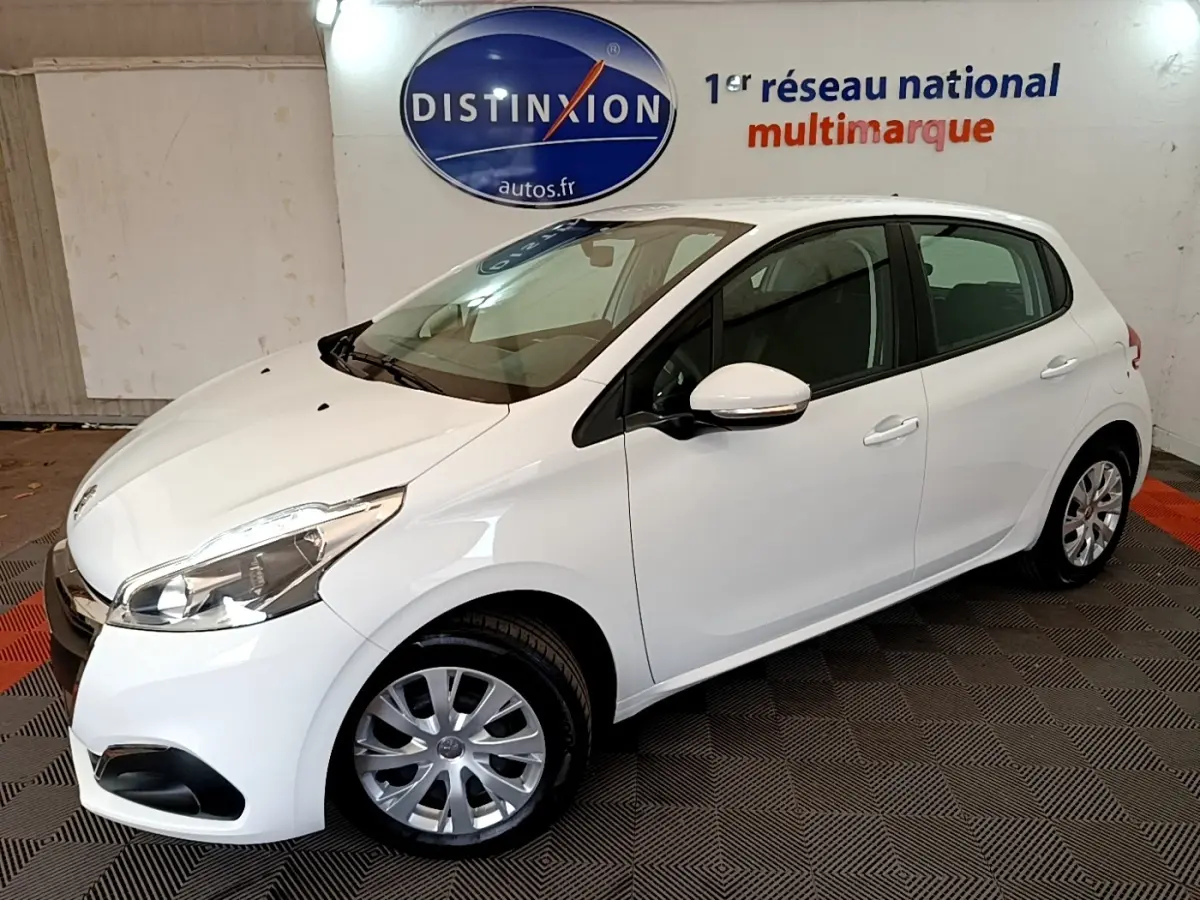 Peugeot 208 blanche vue 3/4 avant droit en intérieur avec jantes acier et rétroviseurs blancs.