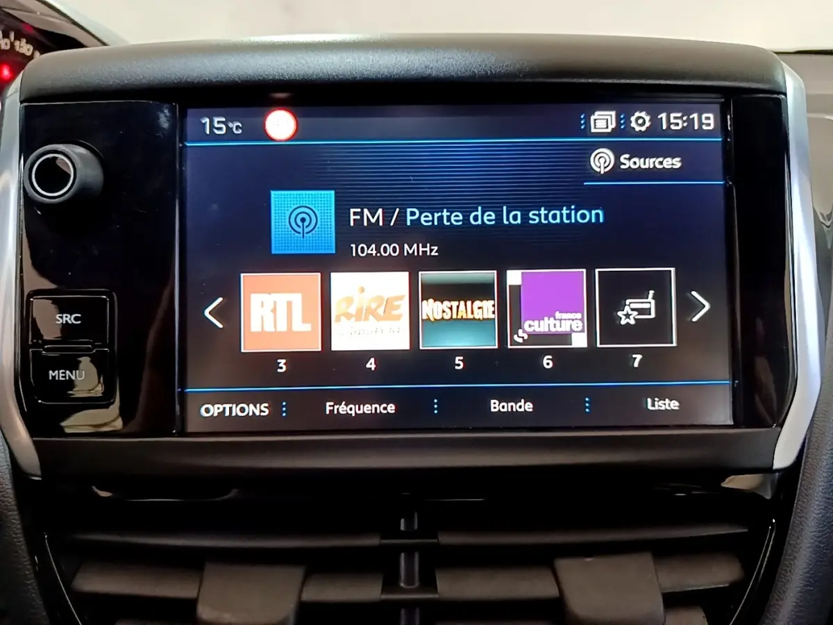 Écran tactile central de la Peugeot 208 blanc, affichant les stations radio FM avec interface moderne.
