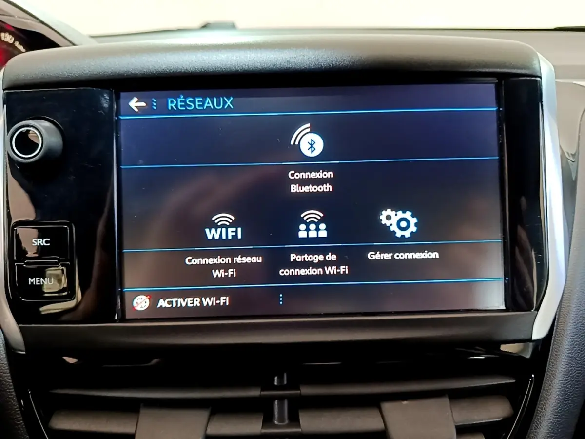Écran tactile central du tableau de bord de la Peugeot 208 blanc, affichant les options de connexion Bluetooth et Wi-Fi.