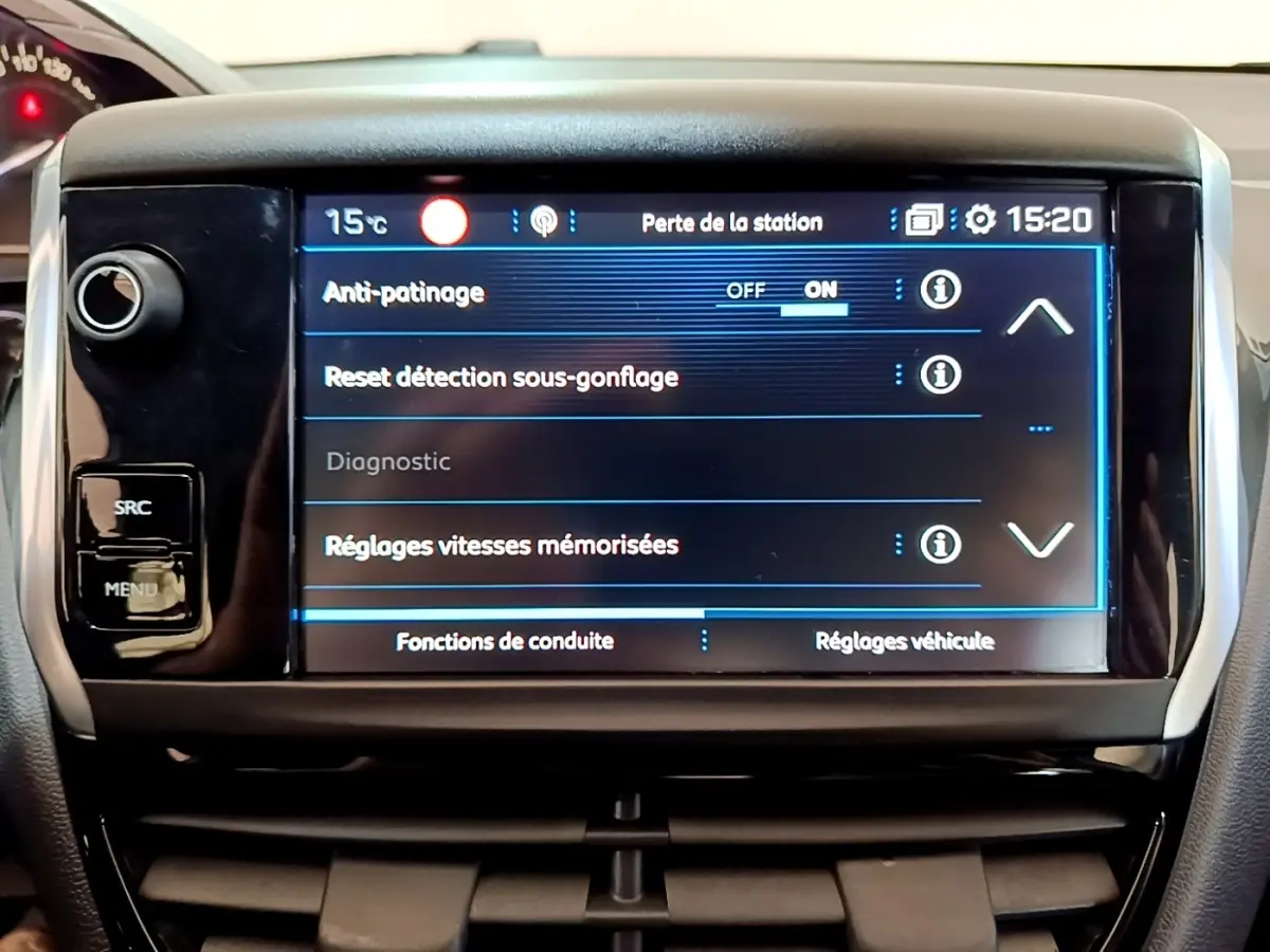Écran tactile central de la Peugeot 208 blanche, affichant les réglages d'anti-patinage et sous-gonflage, vue frontale rapprochée.