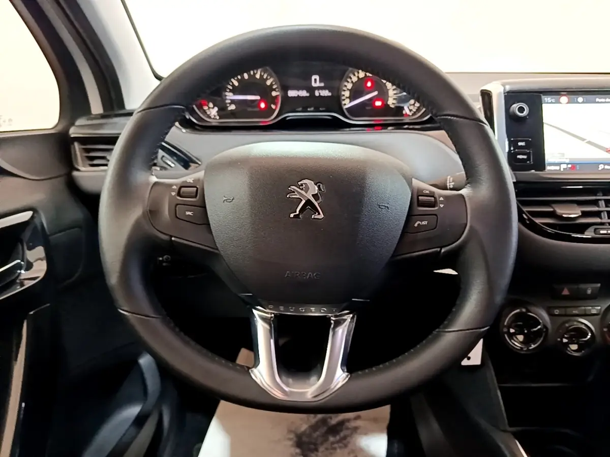 Vue intérieure centrée sur le volant noir de la Peugeot 208 avec tableau de bord et écran tactile visible à droite.