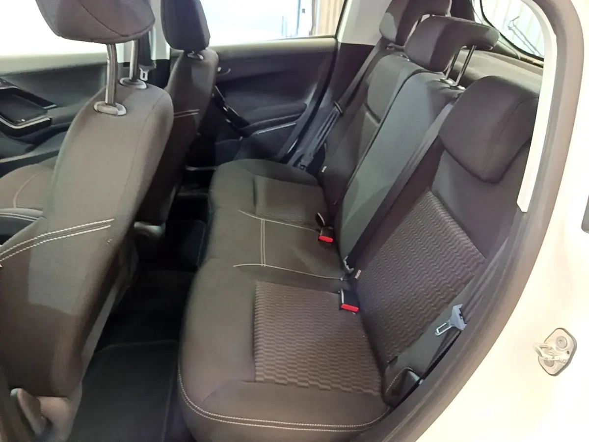 Vue intérieure côté droit des sièges arrière noirs de la Peugeot 208 blanche, montrant les ceintures et appuie-têtes.