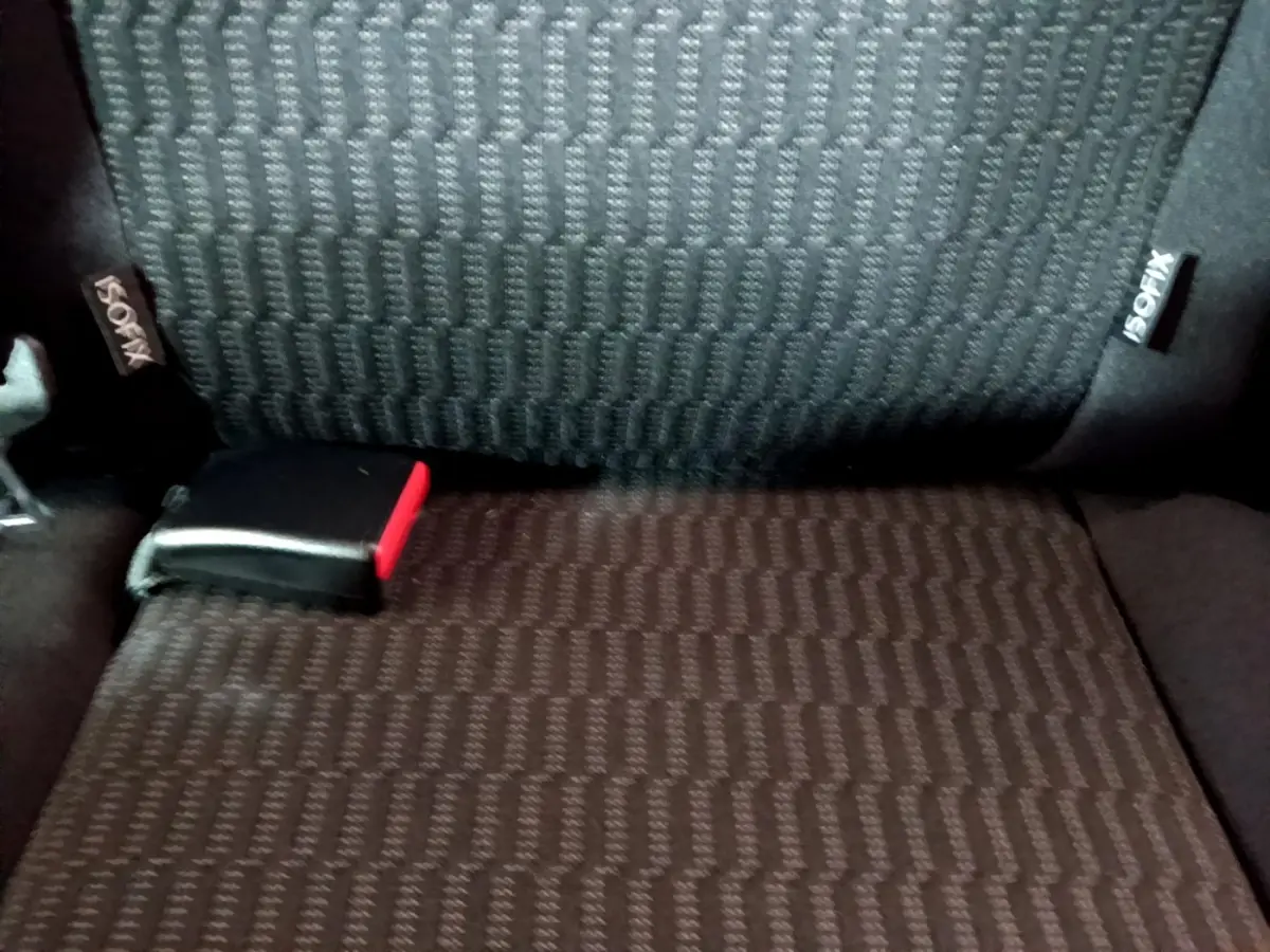 Détail de la banquette arrière noire avec étiquette ISOFIX et boucle de ceinture rouge visible sur une Peugeot 208.