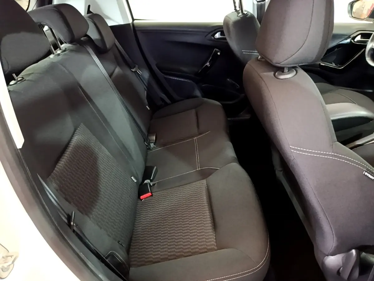 Intérieur arrière de la Peugeot 208 blanche, vue côté gauche, sièges tissu noir avec surpiqûres blanches.