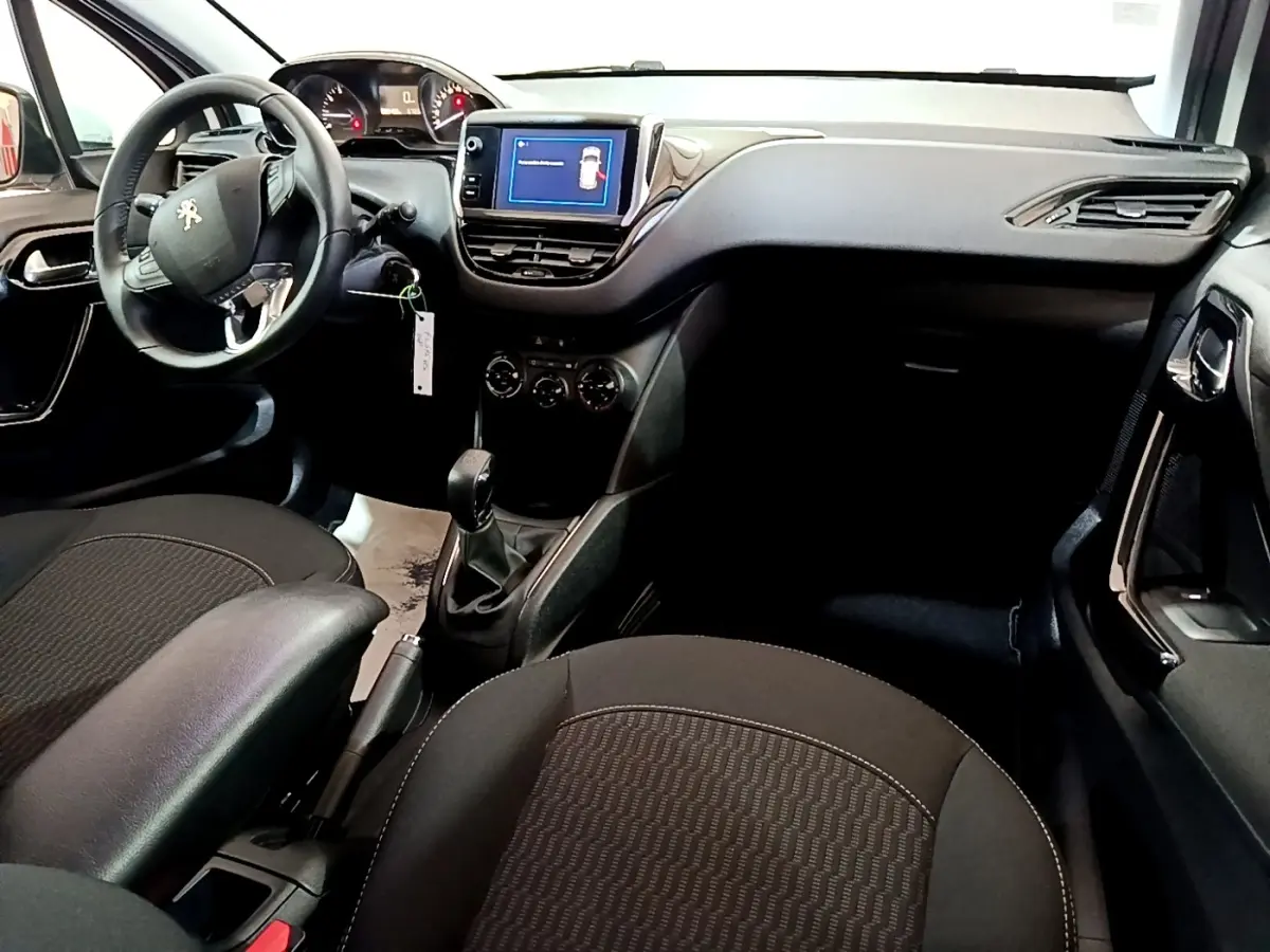 Vue intérieure avant droite de la Peugeot 208 blanche, tableau de bord avec écran tactile et volant multifonction.