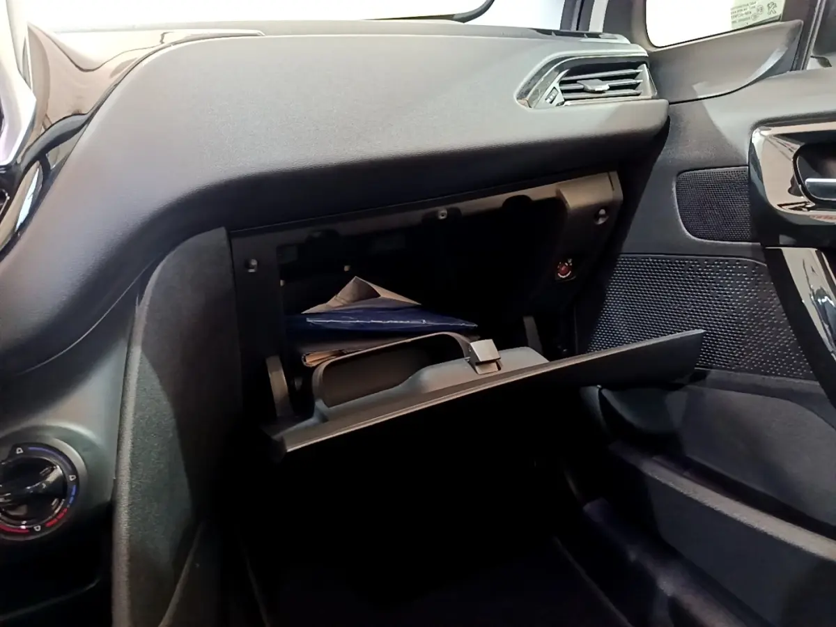 Vue intérieure côté passager de la Peugeot 208 blanche de 2018 avec boîte à gants ouverte et tableau de bord noir.